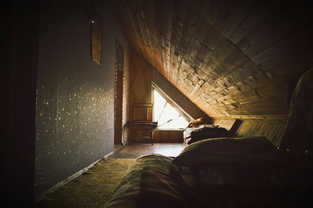 Dachboden mit Bett, Sonnenstrahl und Dachfenster